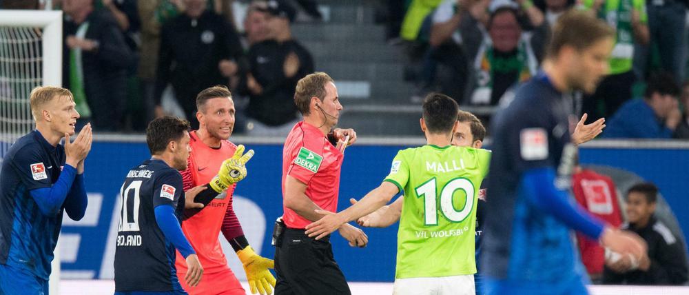 Schiedsrichter Stegemann wird nach einer Elfmeterentscheidung von den Spielern belagert.