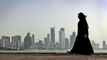 Eine Frau spaziert vor der Skyline der Stadt Doha (Katar). Mehrere arabische Golfstaaten und Ägypten haben die diplomatischen Beziehungen zu Katar abgebrochen.