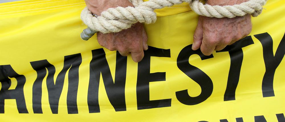 Ein Aktivist von Amnesty International mit symbolischen Fesseln. (Archiv)