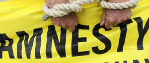 Ein Aktivist von Amnesty International mit symbolischen Fesseln. (Archiv)