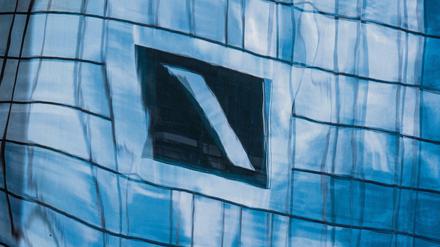 Die Zentrale der Deutschen Bank in Frankfurt am Main spiegelt sich in einer Glasfassade.