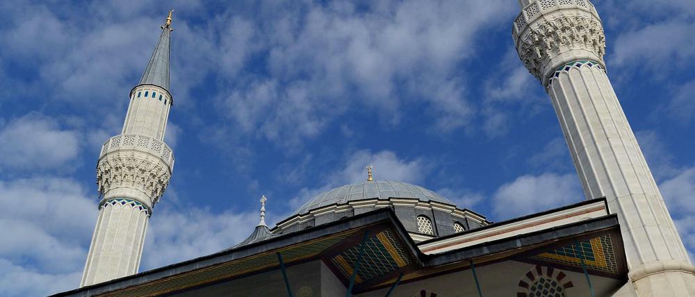 Minarette und Kuppel einer Moschee vor blauem Himmel.