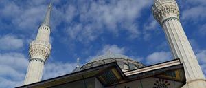 Minarette und Kuppel einer Moschee vor blauem Himmel.