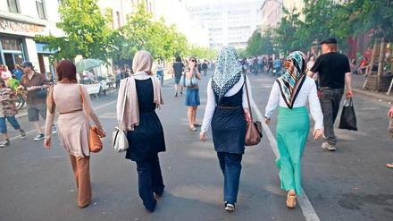Junge Frauen, die Kopftücher tragen, gehen eine Straße herunter.