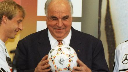 Der Kapitän der Fußball-Nationalmannschaft Jürgen Klinsmann (l) und Jürgen Kohler (r) überreichen 1998 Bundeskanzler Helmut Kohl (M) einen Fußball mit Autogrammen der Mannschaft.