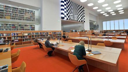 Menschen sitzen in einer Bibliothek an Arbeitstischen.
