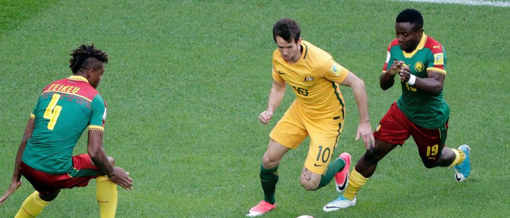 Kameruns Adolphe Teikeu (l) und Collins Fai (r) versuchen Australiens Robbie Kruse den Ball abzunehmen.