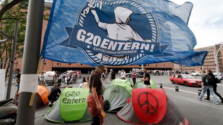 Eine Fahne mit der Aufschrift "G20 entern" weht in Hamburg vor der Elbphilharmonie über einem kleinen Zeltlager von G-20-Gegnern.