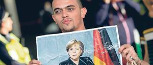Ein junger Mann hält ein Foto der Bundeskanzlerin Angela Merkel hoch.