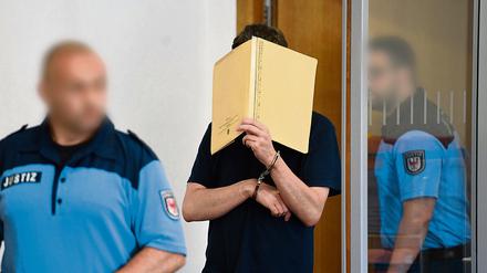 Mit einem Aktenordner vor dem Gesicht betritt Silvio S. in Potsdam den Saal des Landgerichts.