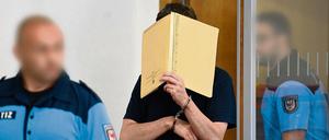 Mit einem Aktenordner vor dem Gesicht betritt Silvio S. in Potsdam den Saal des Landgerichts.