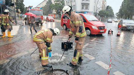 Einsatz am Gullydeckel. Feuerwehrmänner in der überfluteten West-City. 