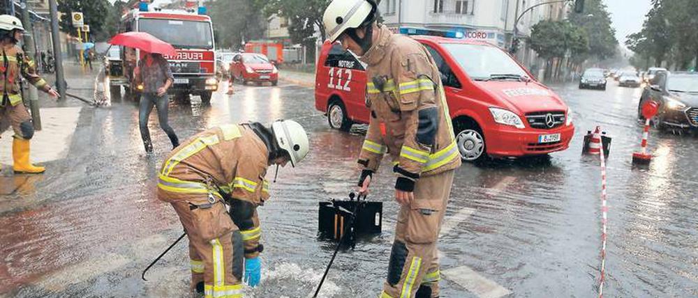 Einsatz am Gullydeckel. Feuerwehrmänner in der überfluteten West-City.