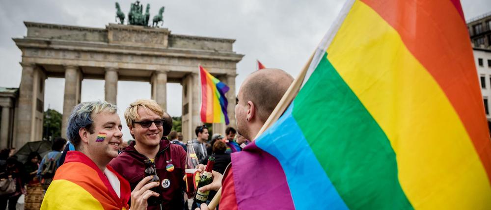 Männer mit Regenbogenflaggen feiern vor dem Brandenburger Tor in Berlin.