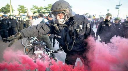 Ein Polizist entfernt eine Rauchbombe während der G20 Welcome to Hell -Demonstration. 