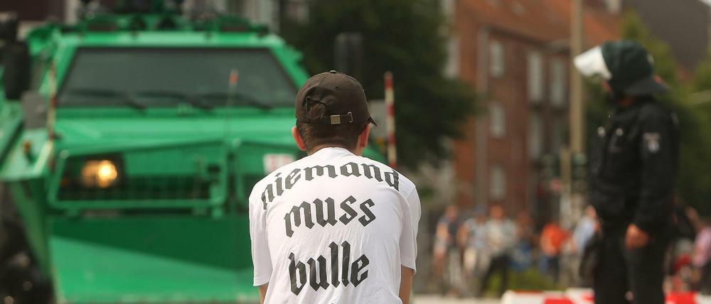 Ein Demonstrant und ein Berliner Polizist am Rande des G20 Gipfels in Hamburg