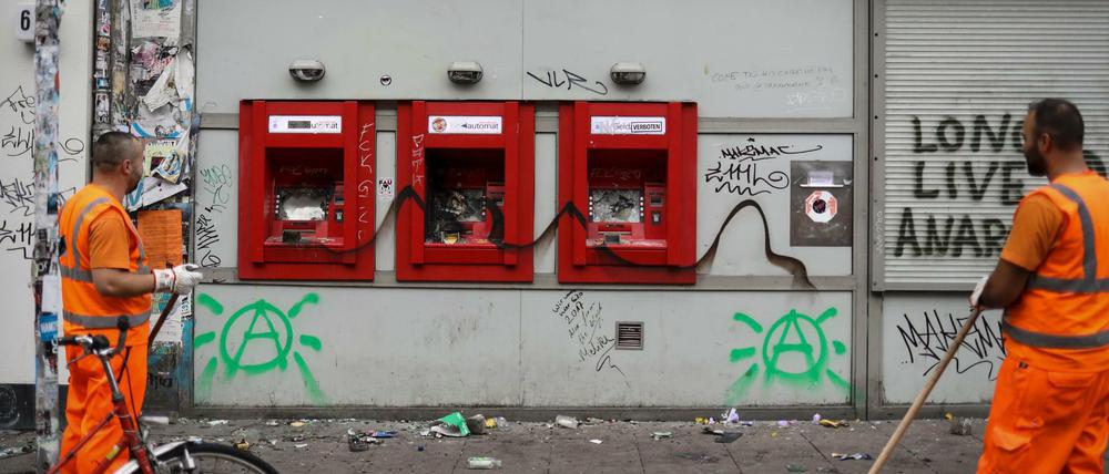 Mitarbeiter der Stadtreinigung säubern die Straße Schulterblatt vor einer Filiale der Sparkasse im Schanzenviertel von den Verwüstungen aus der Nacht.