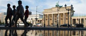 Passanten gehen nach einem kurzen, aber heftigen Regenschauer am Brandenburger Tor vorbei.