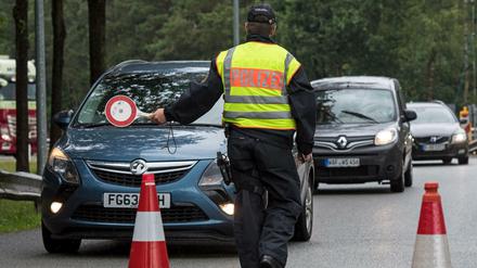 Ein Beamter der Bundespolizei leitet den Einreiseverkehr aus den Niederlanden zur Kontrolle über einen Parkplatz.