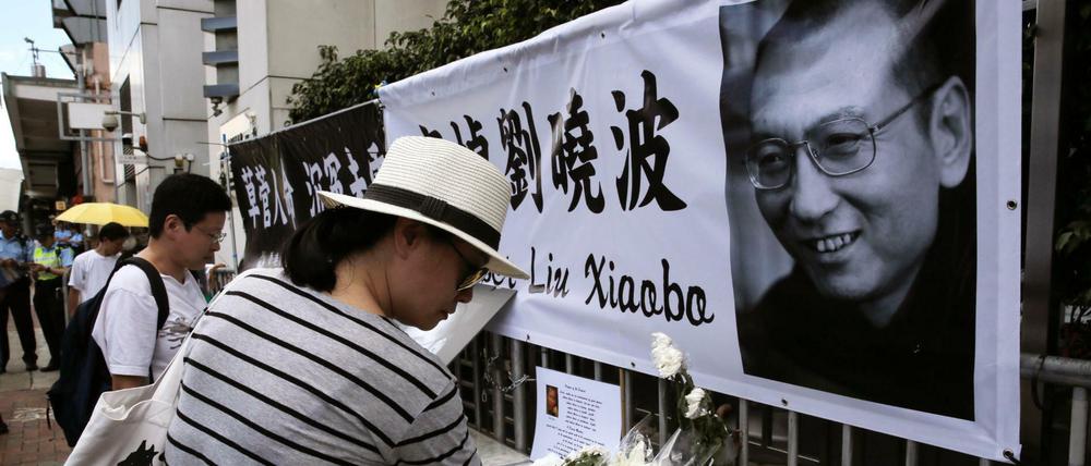 Eine Frau legt am in Hongkong Blumen für den verstorbenen chinesischen Friedensnobelpreisträger Liu Xiaobo nieder.