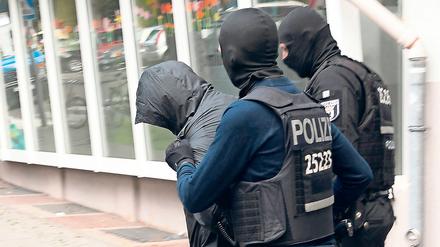 Polizeibeamte führen in Neukölln einen der mutmaßlichen Diebe ab.
