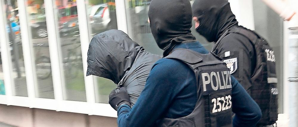 Polizeibeamte führen in Neukölln einen der mutmaßlichen Diebe ab.