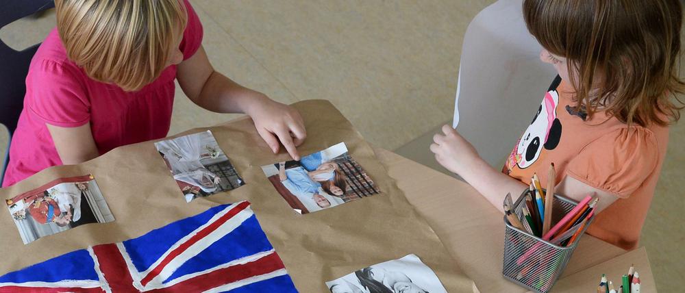 Leonie (li.) und Lilly bereiten im Kinder- und Jugendhaus "Bolle" ein Plakat vor, auf dem die britische Flagge und Fotos von William und Kate zu sehen sind. 