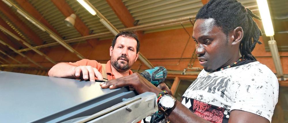 Asylbewerber Omar Ceesay (r) arbeitet in der Schreinerei Holitsch in Tettnang-Hiltensweiler (Baden-Württemberg) an einer Tür.