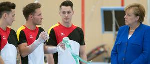 Angela Merkel lässt sich von Andreas Toba, Andreas Bretschneider und Marcel Nguyen (von rechts) die Feinheiten des Turnens erklären.