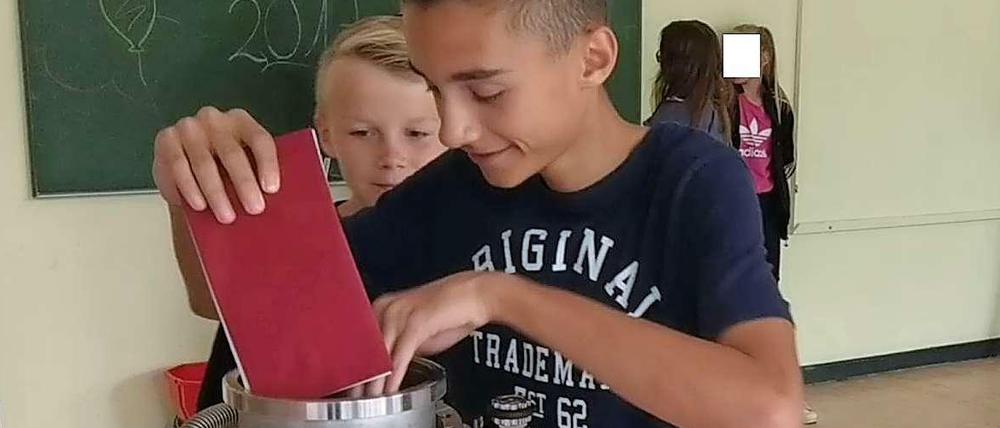 Zwei Schüler werfen ihre Briefe in die Zeitkapsel.