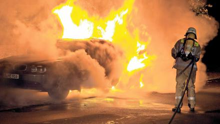 Feuerwehrleute löschen ein brennendes Auto in Berlin-Kreuzberg (Archivbild vom 25.08.2011).