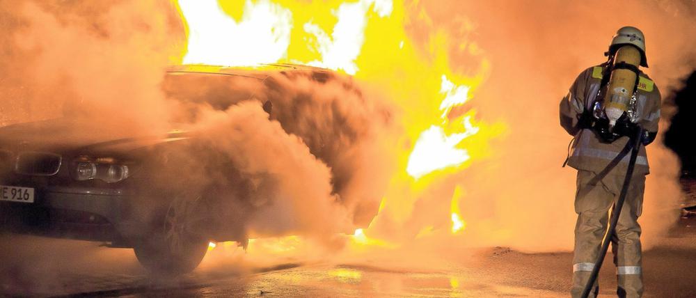 Feuerwehrleute löschen ein brennendes Auto in Berlin-Kreuzberg (Archivbild vom 25.08.2011). 