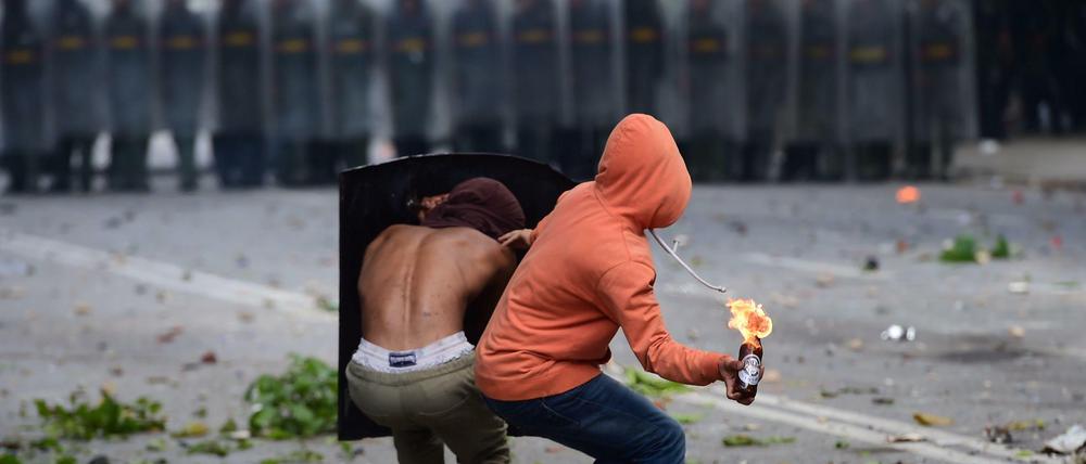 Demonstranten werfen einen Brandsatz auf Polizisten bei Protesten in Venezuela.