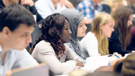Studierende mit und ohne Kopftuch sitzen in einem Hörsaal.