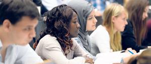 Studierende mit und ohne Kopftuch sitzen in einem Hörsaal.