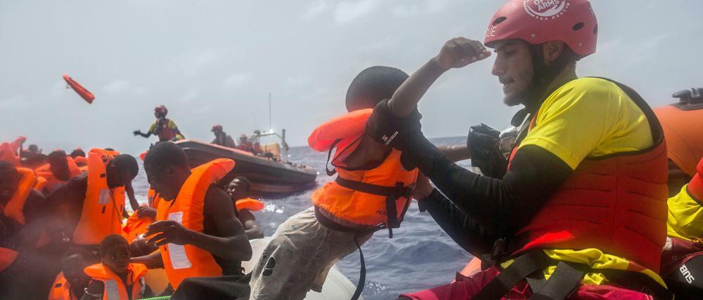 Ein Mitarbeiter der spanischen NGO «Proactiva Open Arms» hebt am 25.07.2017 vor der libyschen Küste ein Kind vom einem Flüchtlingsboot.