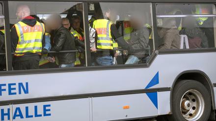 Vor der Abreise: Bundespolizisten in neongelben Westen begleiten abgelehnte Asylbwerber in einem Flughafen-Zubringer-Bus.
