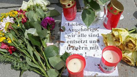 Blumen und Kerzen liegt an einer Bushaltestelle vor dem Supermarkt in Hamburg-Barmbek.