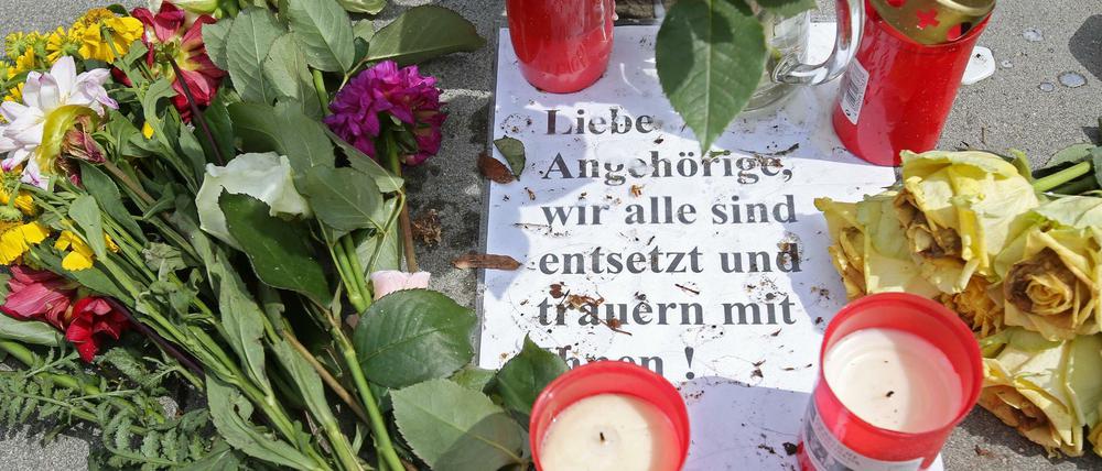 Blumen und Kerzen liegt an einer Bushaltestelle vor dem Supermarkt in Hamburg-Barmbek.