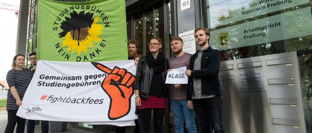Jungen Menschen stehen vor einem Gerichtsgebäude und halten Transparente hoch, eines trägt die Aufschrift "Gemeinsam gegen Studiengebühren".