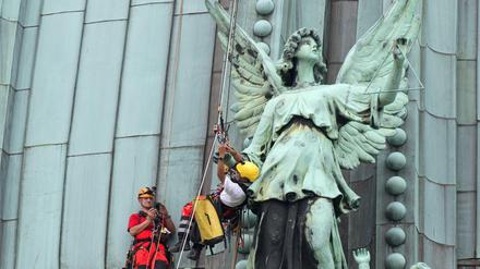 Industriekletterer montieren auf dem Dach des Berliner Doms in Berlin einen Triangelstab an einem Kupferengel. 