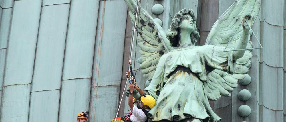 Industriekletterer montieren auf dem Dach des Berliner Doms in Berlin einen Triangelstab an einem Kupferengel. 