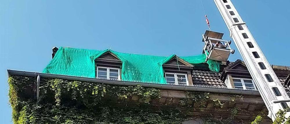 Aus einem Arbeitskorb befestigten Spezialisten das Netz auf dem Dach.