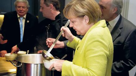 Bundeskanzlerin Merkel füllt in einer Suppenküche eine Schale mit Suppe.