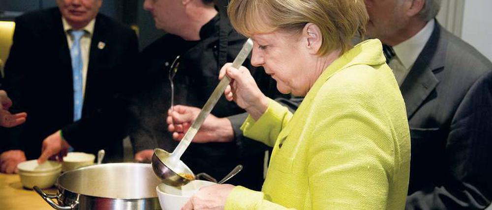 Bundeskanzlerin Merkel füllt in einer Suppenküche eine Schale mit Suppe.