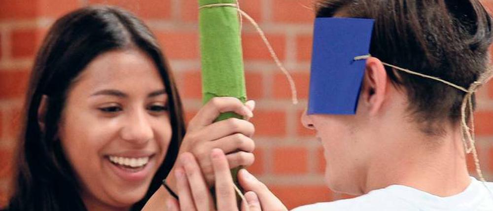 Eine Pädagogin von "Schlaufuchs Berlin" beim Piñatas-Spiel mit einem Flüchtlingsjungen im Barnim-Gymnasium.