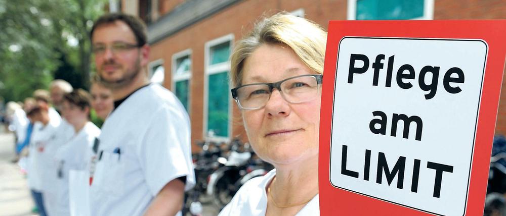 Eine Pflegerin demonstriert damit gegen Überbelastung in ihrem Job.