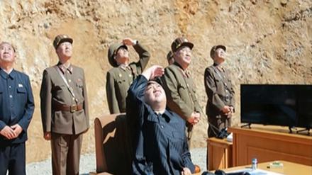 Den nordkoreanischen Machthaber Kim Jong Un (M) begutachtet einen Raketenstart.