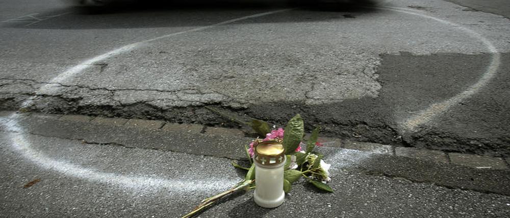 Eine Kerze und Blumen erinnern an einen tödlichen Verkehrsunfall.