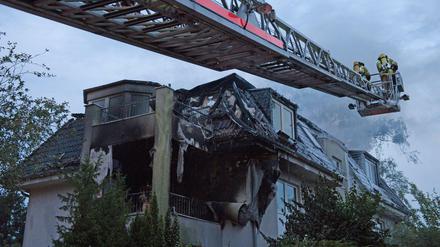 Zwei Feuerwehrleute löschen die letzten Flammen in einem Dachstuhl eines Hauses an der Goerzallee